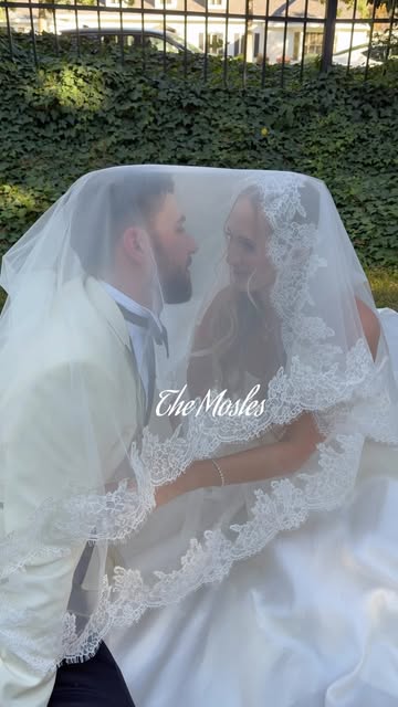 Newlyweds sharing a quiet moment beneath a lace veil